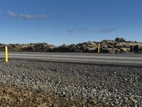 a person riding their skateboard in a parking lot near some rocky terrain and a yellow post