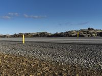 a person riding their skateboard in a parking lot near some rocky terrain and a yellow post