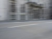 a man on a skateboard is speeding down the road in motion of a blurred building