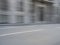 a man on a skateboard is speeding down the road in motion of a blurred building