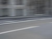 a man on a skateboard is speeding down the road in motion of a blurred building