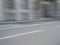 a man on a skateboard is speeding down the road in motion of a blurred building