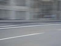 a man on a skateboard is speeding down the road in motion of a blurred building