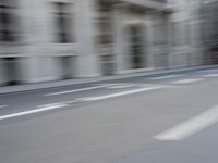 a man on a skateboard is speeding down the road in motion of a blurred building