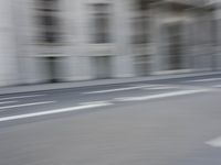 a man on a skateboard is speeding down the road in motion of a blurred building