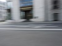 a man on a skateboard is speeding down the road in motion of a blurred building