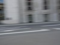 a man on a skateboard is speeding down the road in motion of a blurred building