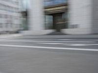 a man on a skateboard is speeding down the road in motion of a blurred building