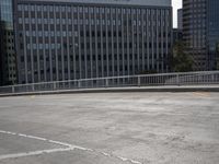 a skateboarder is riding across the street in an empty lot near a high rise apartment building