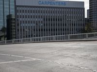 a skateboarder is riding across the street in an empty lot near a high rise apartment building