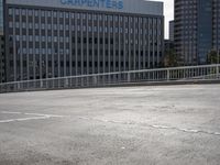 a skateboarder is riding across the street in an empty lot near a high rise apartment building