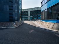 a person riding a skate board up a ramp down a sidewalk towards a building in a city