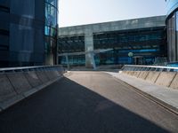 a man riding a skateboard on the pavement of an empty street past large glass buildings