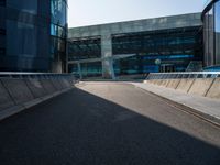 a man riding a skateboard on the pavement of an empty street past large glass buildings