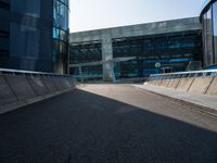 a man riding a skateboard on the pavement of an empty street past large glass buildings