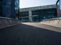 a man riding a skateboard on the pavement of an empty street past large glass buildings