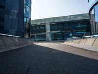 a man riding a skateboard on the pavement of an empty street past large glass buildings