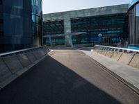 a man riding a skateboard on the pavement of an empty street past large glass buildings