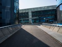 a man riding a skateboard on the pavement of an empty street past large glass buildings