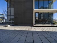 a person with a skateboard near some windows and a building under a clear blue sky