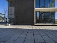 a person with a skateboard near some windows and a building under a clear blue sky