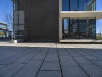 a person with a skateboard near some windows and a building under a clear blue sky