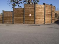 a young boy riding a skateboard on the street in front of an fence and tree