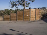 a young boy riding a skateboard on the street in front of an fence and tree