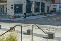 a person riding a skateboard on a city sidewalk next to tall buildings and benches