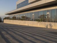 the man skateboards on an asphalt surface near the building and street sign on a clear blue sky