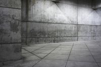 a man skateboarding in the center of an empty room with concrete walls and flooring
