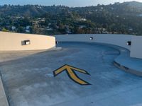 a man is standing on a skateboard on the edge of a roof with a big arrow painted in the concrete