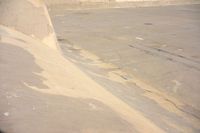 a young skateboarder performing a trick at the top of a ramp in front of a concrete wall