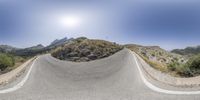 a man riding his skateboard on a long concrete ramp in a mountain area under a clear blue sky