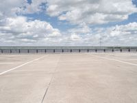 a lone man riding his skateboard across the tarmac of an airport near the water