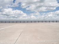 a lone man riding his skateboard across the tarmac of an airport near the water