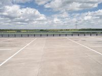 a lone man riding his skateboard across the tarmac of an airport near the water