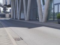 the man is riding his skateboard near the modern building's entrance, near other modern buildings