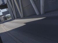 the man is riding his skateboard near the modern building's entrance, near other modern buildings