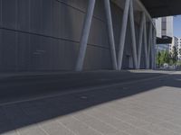 the man is riding his skateboard near the modern building's entrance, near other modern buildings