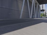 the man is riding his skateboard near the modern building's entrance, near other modern buildings