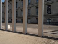 a person skateboarding next to some large building with lots of windows and stone columns