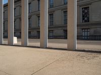 a person skateboarding next to some large building with lots of windows and stone columns