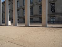 a person skateboarding next to some large building with lots of windows and stone columns