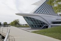 people riding on a skateboard past a building with a curved roof that has large windows