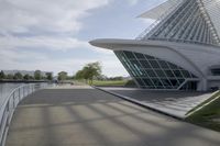 people riding on a skateboard past a building with a curved roof that has large windows