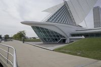 people riding on a skateboard past a building with a curved roof that has large windows