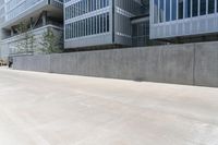 a skateboarder rides a skate board down an empty concrete street near a high - rise office building