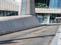 a man is skateboarding on a paved walkway near some modern buildings at an angle