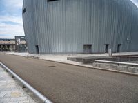 a skateboarder riding near a skate ramp in front of a large building with two round openings